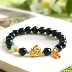 Premium Hetian jade Year of the Horse bracelet featuring black obsidian beads and gold-plated horse ornament on open book