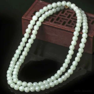 Jade 108 bead mala in pale light green laid on carved wooden jewelry display box - shows uniform hand-polished round beads with gold metal clasp perfect for meditation practice