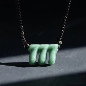 Natural green jade triple seven angel number necklace side profile close-up detail view highlighting smooth carved stone with woven brown cord