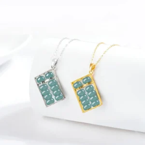 Pair of jade abacus necklace pendants in gold and silver tone displayed on white cylindrical stand, showing both metal color options