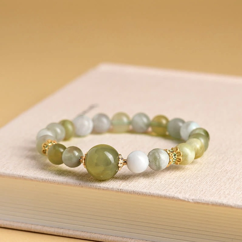 Mixed green jade beaded bracelet with smooth round beads and gold spacers on book display