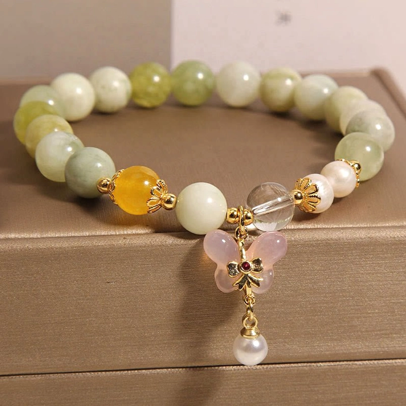 Warm-toned jade agate beads bracelet with butterfly pendant displayed in leather jewelry case, overhead view