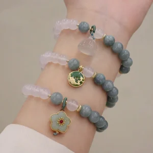 Woman wearing grey-blue jade and translucent white agate peace buckle and lotus flower elastic bracelets close-up wrist view