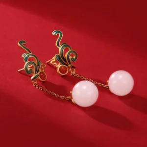 Pair of white jade red agate drop earrings top-down view, showing enamel phoenix design and gold chain detail