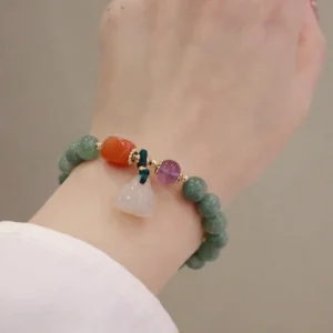 Green jade healing bracelet worn on wrist with side profile view, showing mixed crystal beads and dark green knot details