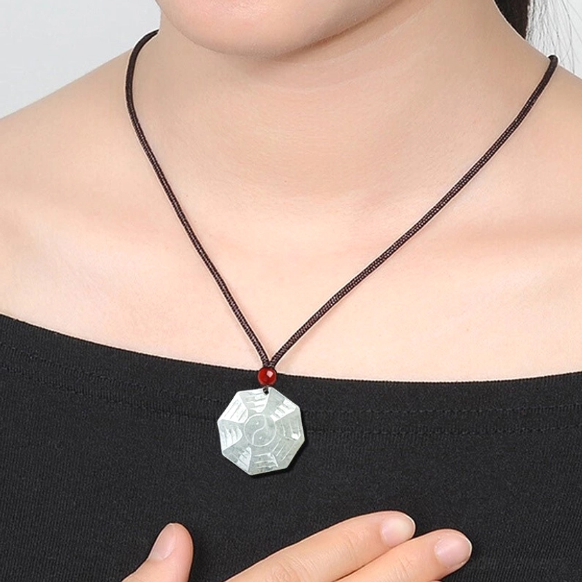 Woman wearing jade Bagua Yin Yang necklace at collarbone with brown wax cord and red agate bead accent on skin
