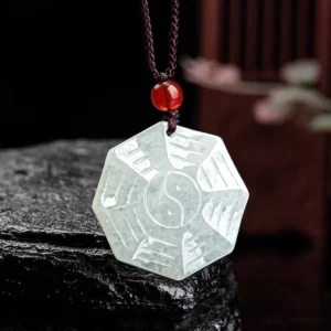Natural jade Bagua Yin Yang pendant necklace with hand-carved trigrams and tai chi symbol on dark stone background - front view detail