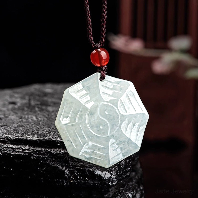 Natural jade Bagua Yin Yang pendant necklace with hand-carved trigrams and tai chi symbol on dark stone background - front view detail
