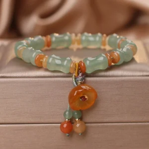 Natural jade bamboo beaded bracelet with orange agate flower charm displayed on white satin jewelry box