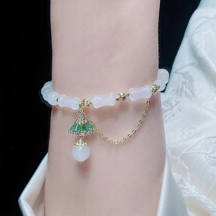 Jade bamboo bracelet worn on forearm showing how the elastic fits comfortably, with light fabric background emphasizing the white stone's luminous quality