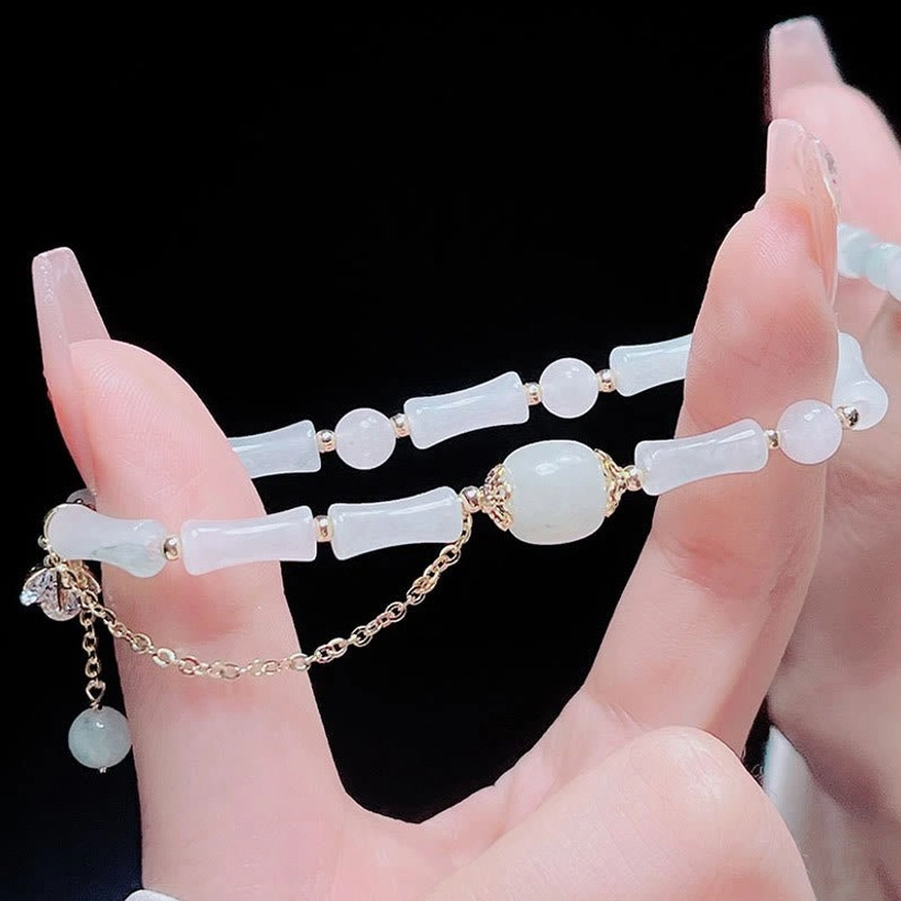 Luxury jade bamboo bracelet elastic cord detail with gold-tone hardware fittings and decorative charms, showing premium craftsmanship