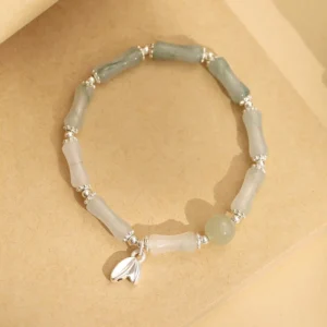 925 sterling silver bamboo charm with natural jade beads on kraft paper background flat lay