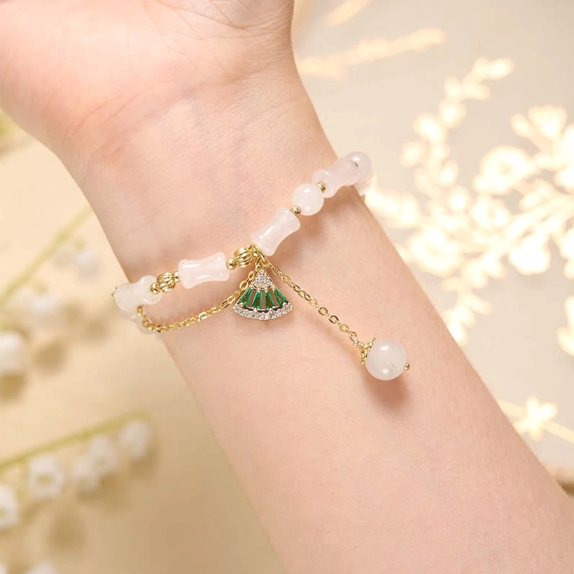 Woman wearing Tianshan white jade bamboo bracelet on wrist with floral background, showing how the bracelet looks when worn