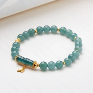 Side angle view of green jade beads and polished bamboo-shaped jade ornament, featuring smooth natural stone texture and gold metal connectors