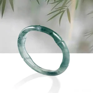 Hand-carved jade bamboo prosperity ring - three-quarter overhead angle displaying bamboo joint detailing on teal green jade