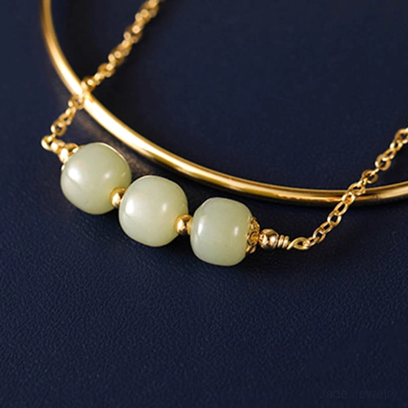 Detailed side close up of double layer jade bangle bracelet showing barrel shaped light green jade beads on dark blue tray