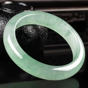 Jade bangle bracelet side profile showing smooth rounded band and authentic light green jade stone color