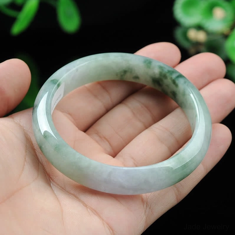 Jade bangle bracelet worn on hand showing proper sizing and fit, green spotted jade design on palm