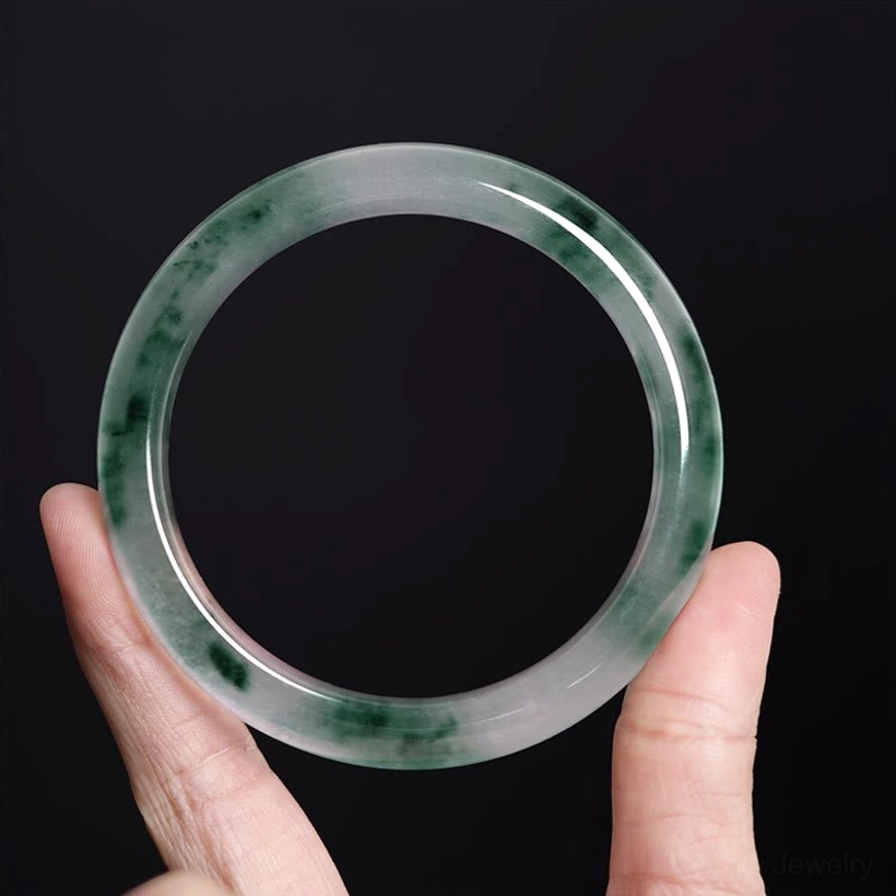 Front view of jade floating flower bangle held in hand, displaying translucent quality and green veins
