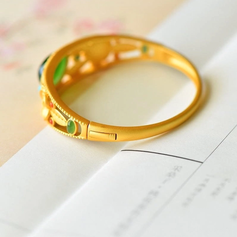 Hollow gold filigree jade bangle with hinged clasp, colored gem accents, and delicate floral carving detail
