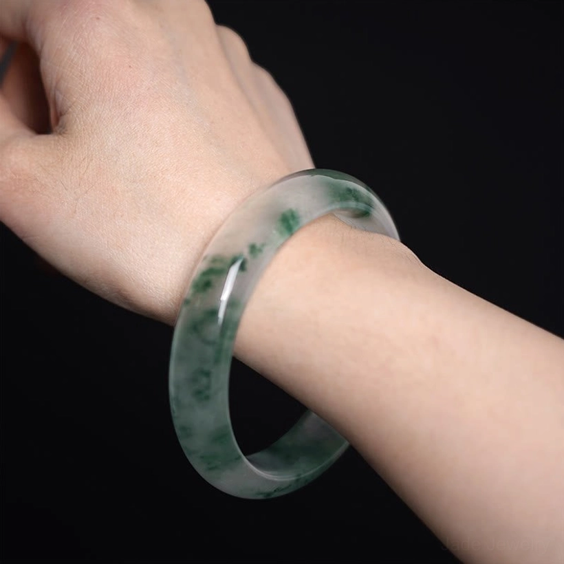 Natural jade bangle worn on adult wrist, showing size fit and beautiful green floating pattern