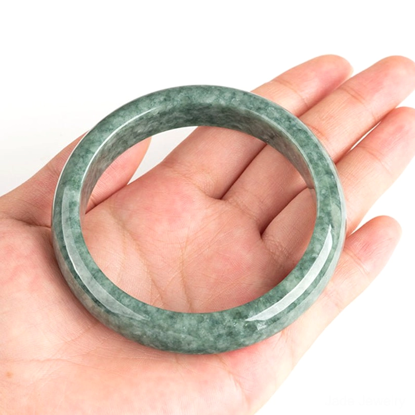 Jade bangle bracelet held in palm close-up, showing inner diameter and fit for sizing reference