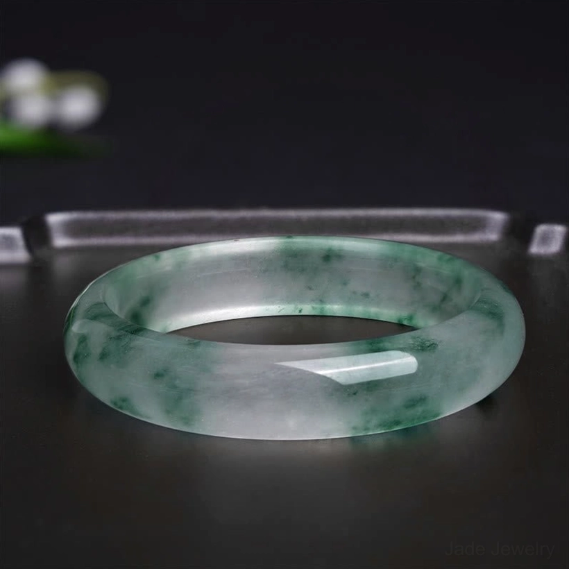 Top-down view of natural jade bangle showing complete floating flower pattern and marbled texture