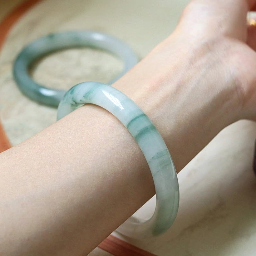 Natural jade bangle bracelet worn on left wrist side view, demonstrating secure fit and elegant rounded band with green veining