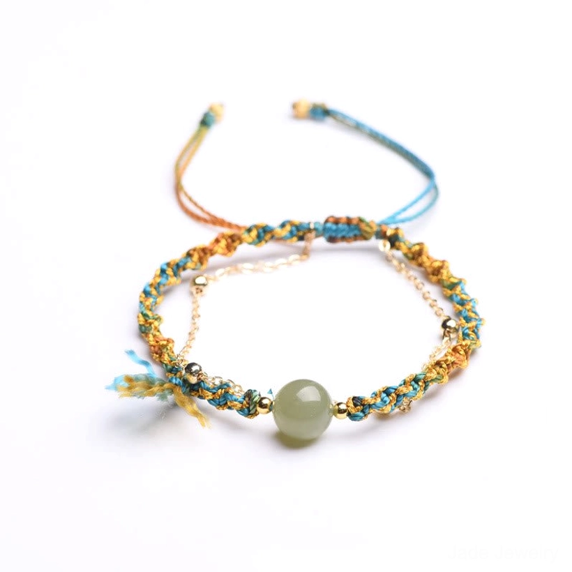Double layer jade bead bracelet with metal chain and adjustable string closure on wooden table