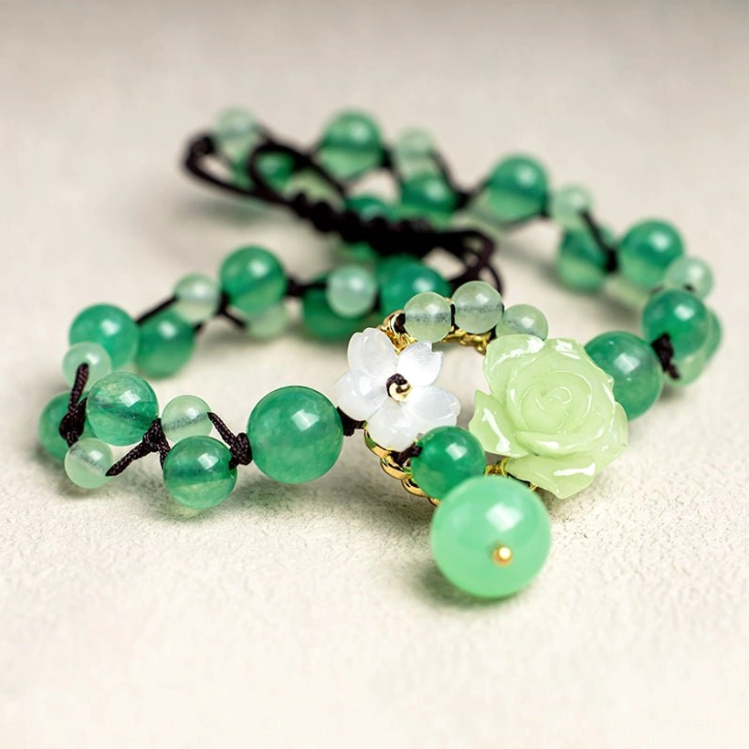 Close-up flat lay showcasing multiple natural jade beads and hanging round jade bead detail of the braided anklet