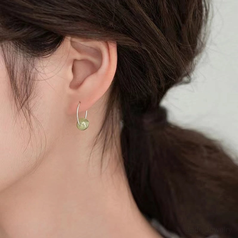 Jade bead earrings worn on ear - delicate green jade drop sterling silver studs in real daily wear scenario showing subtle elegant fit
