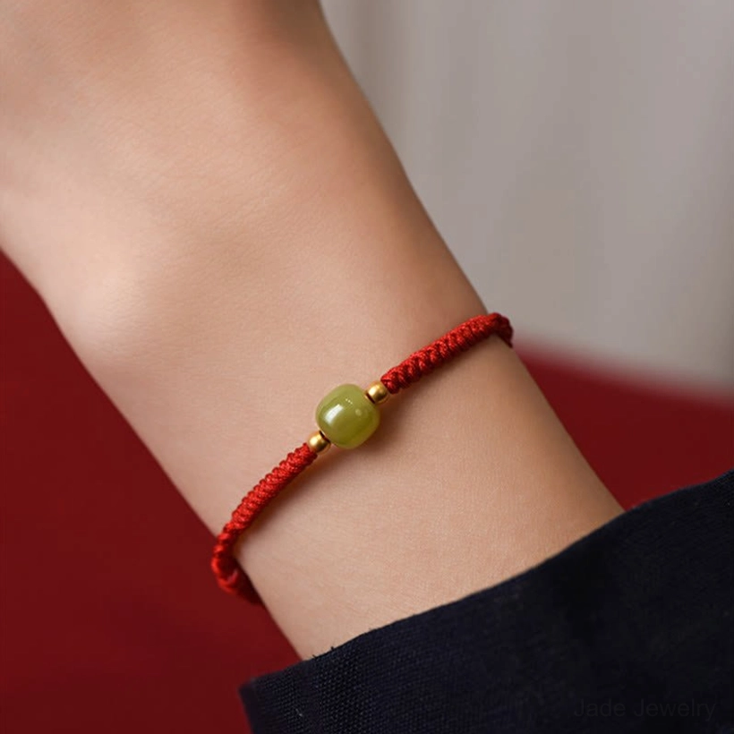 Natural Hetian jade green bead with gold spacer on red cord detail