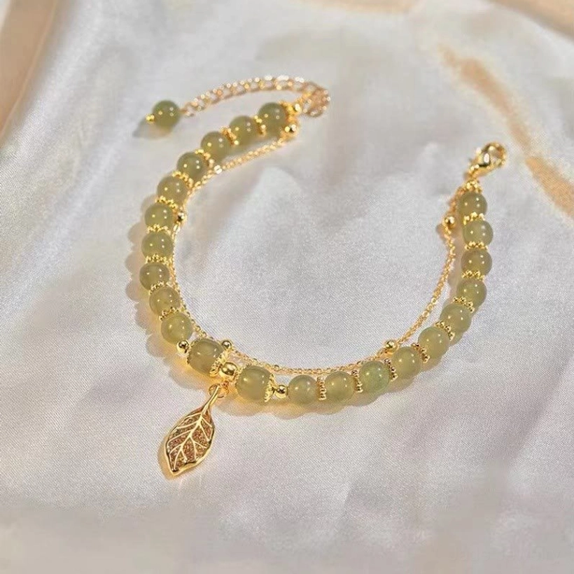 Single-layer mixed jade beads bracelet with gold spacers and leaf pendant on white silk