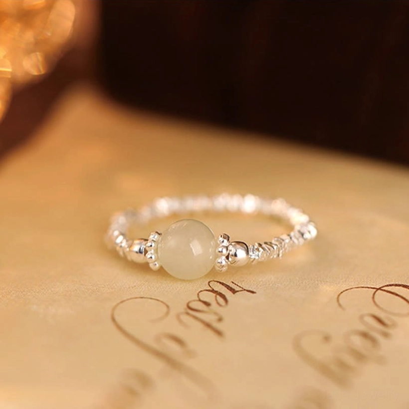 Minimalist Hetian jade beaded ring with smooth pale stone on textured paper background