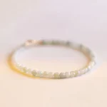 Delicate 2mm pale green jade beads bracelet with 14k gold-plated copper clasp, front close-up flat lay showing uniform bead arrangement