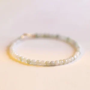 Delicate 2mm pale green jade beads bracelet with 14k gold-plated copper clasp, front close-up flat lay showing uniform bead arrangement