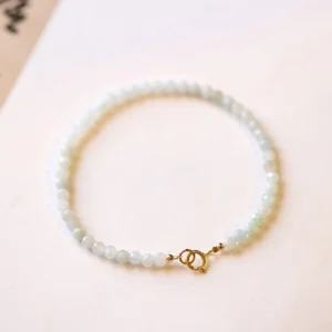Ultra-thin jade beaded bracelet top-down view featuring small round jade beads with gold spring clasp on light background