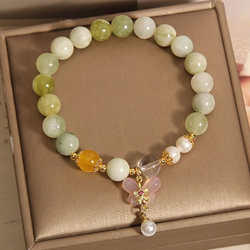 Close-up flat lay of jade bracelet showing charm and bead arrangement with gold hardware accents