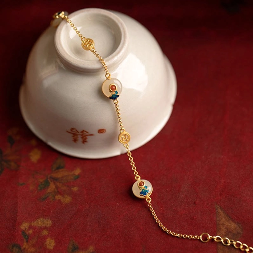 Auspicious Clouds Jade Bracelet draped over Chinese porcelain calligraphy bowl showcasing gold hardware and cultural styling
