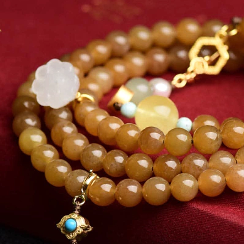 Close-up overhead view of beaded jade bracelet showing individual brown jade beads and white lotus focal point