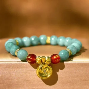 Close-up detail of matte green jade beads with rotating gold Om Mani Padme Hum charm and red sacred mantra beads