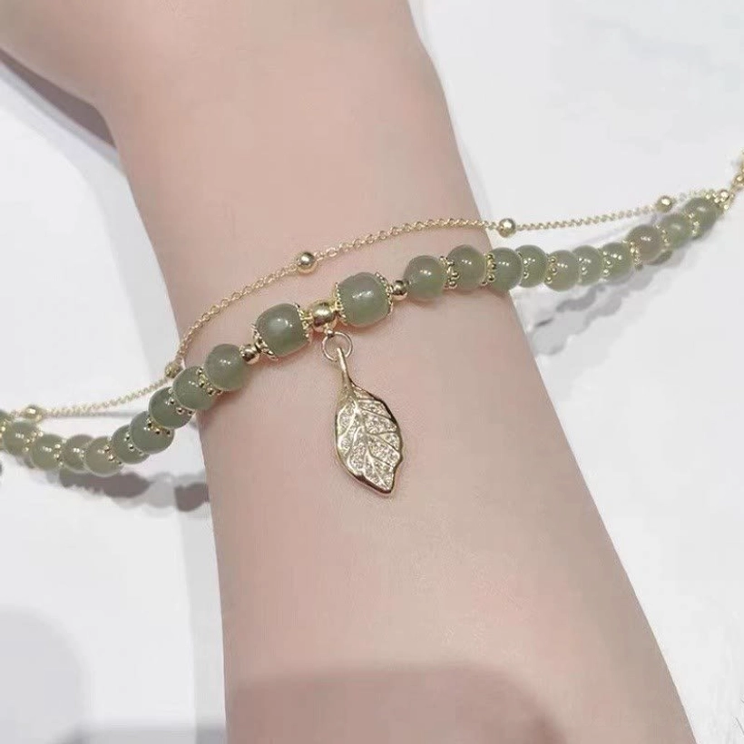 Dark green jade stone beads bracelet with gold hardware and hollow leaf charm closeup