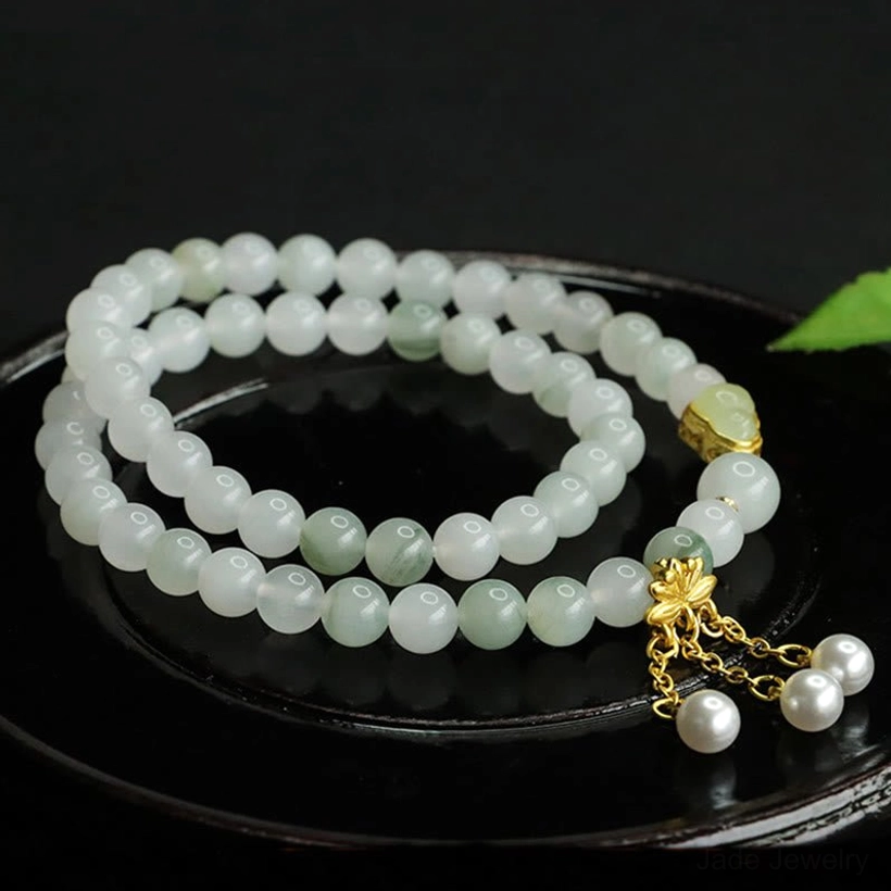 Jade lotus bracelet double loop design showcasing light green Tianshan jade beads with gold hardware and dual pearl pendant accents