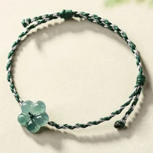 Flat lay top-down view of green and white jade bracelet with delicate jade four-leaf flower charm