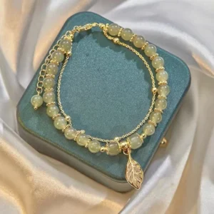 Light green jade stone beads bracelet with gold chain and hollow leaf charm on velvet holder