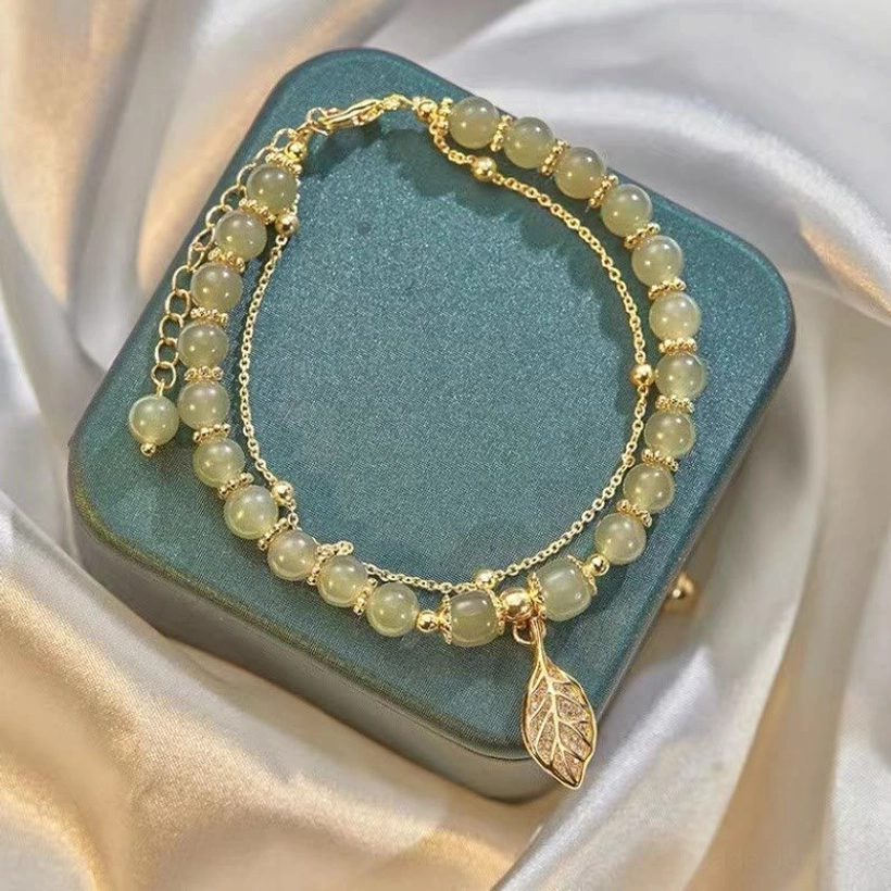 Light green jade stone beads bracelet with gold chain and hollow leaf charm on velvet holder
