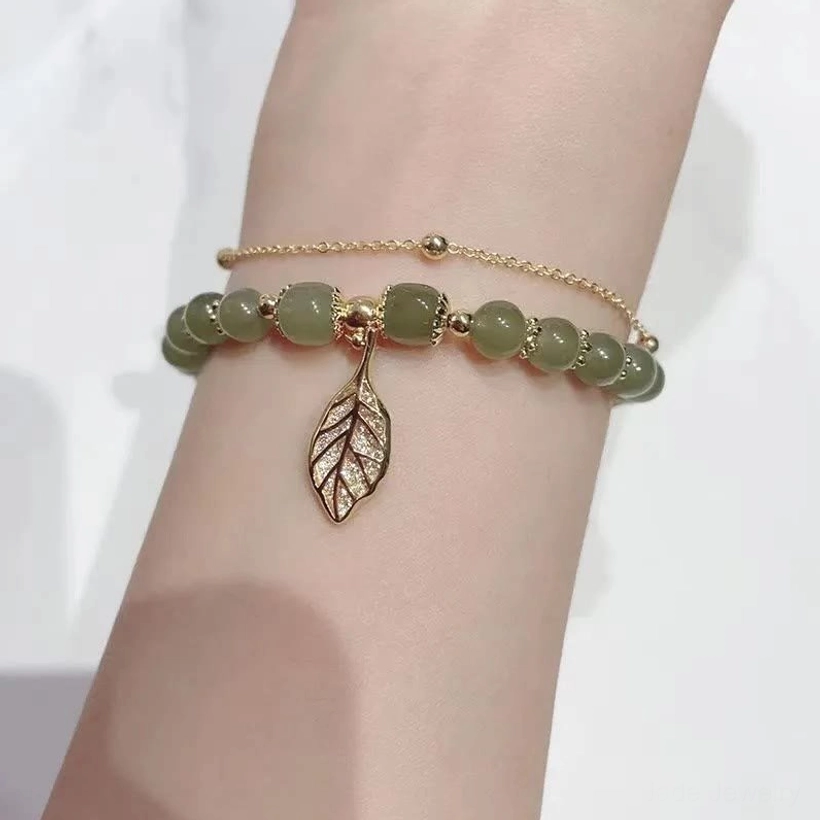 Light green jade beads bracelet with gold chains and hollow leaf pendant on wrist