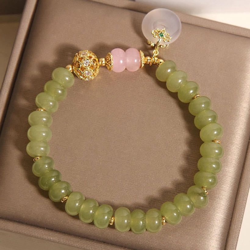 Close-up detail of jade peace buckle bracelet showing green jade beads, rose quartz, chalcedony pendant, and gold accents