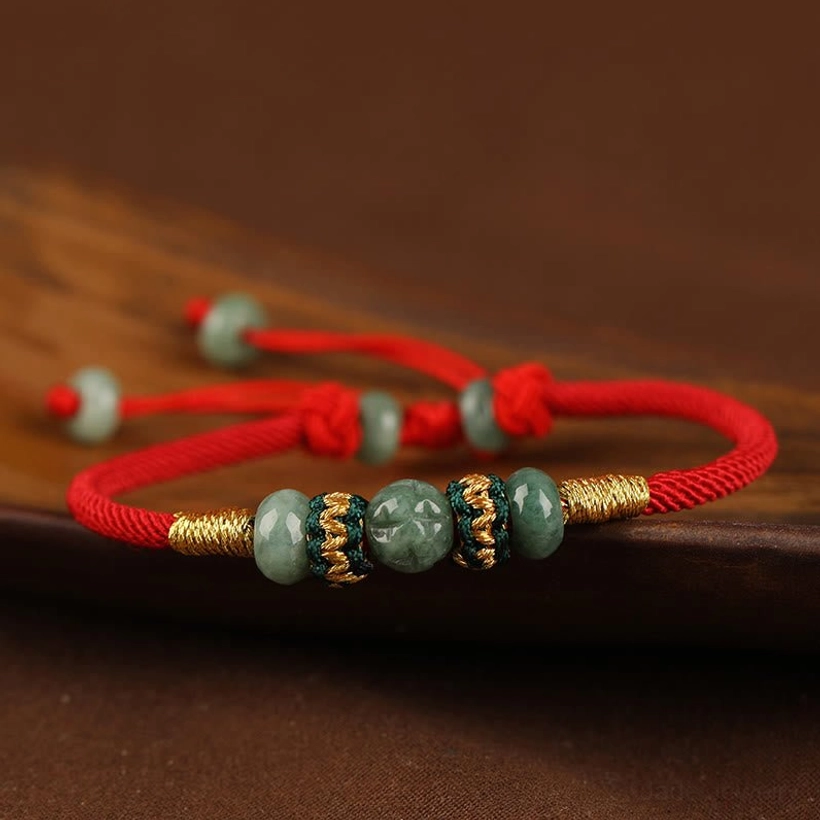 Red string jade prosperity bracelet with gold accents showing end bead details and adjustable fit