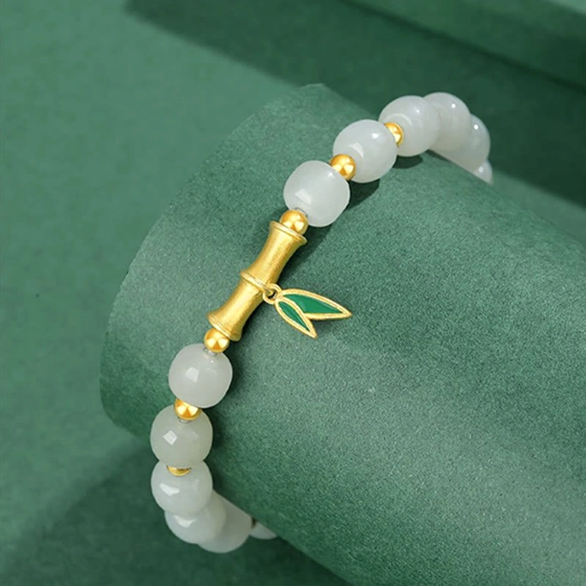 Side view of Hetian jade bracelet displaying bamboo joint metal spacer and sterling silver leaf charm detail